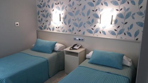 普拉森西亚Hostal La Despensa de Extremadura的蓝色客房内的两张单人床