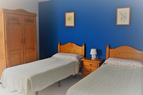 塞博河畔卡莱塔Apartamentos herederos Lm的一间卧室设有两张床和蓝色的墙壁