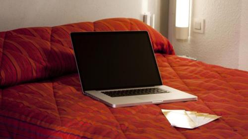 圣热尼普伊普瑞米尔杰内夫圣杰尼普利经典酒店的床上的笔记本电脑