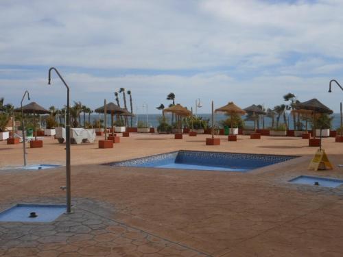 阿尔姆尼卡Apartamento 1a linea playa com piscina Almuñécar的庭院设有游泳池和遮阳伞。