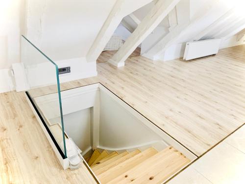 乌斯特卡Apartamenty VIP的白色客房的玻璃楼梯,铺有木地板