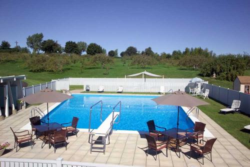 Châteauguay Heights迪由维尔乡间别墅酒店的一个带桌椅和遮阳伞的游泳池