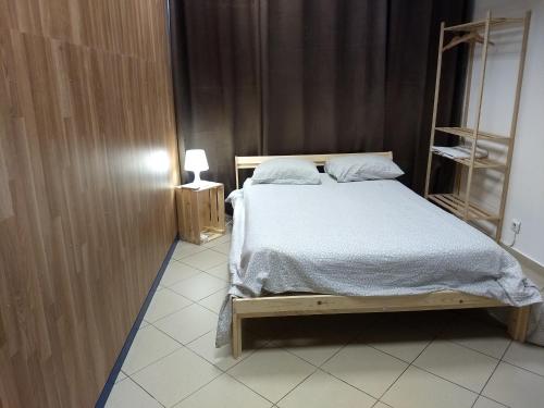 法鲁Melaya Budget Hostel的卧室配有一张床和一盏灯,铺有瓷砖地板。