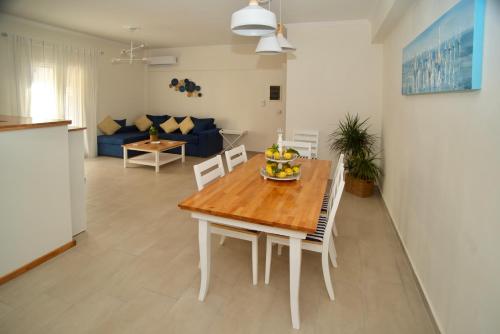 科孚镇The Bluehouse - Spacious top floor flat with parking, by Mon Repos beach的厨房以及带木桌和椅子的客厅。