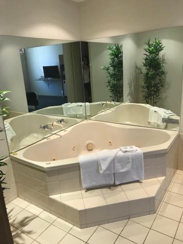 阿德莱德Bay Motel Hotel的带浴缸和镜子的大浴室