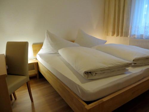 拉特恩斯豪斯马特酒店的一张带白色床单的床和一把椅子