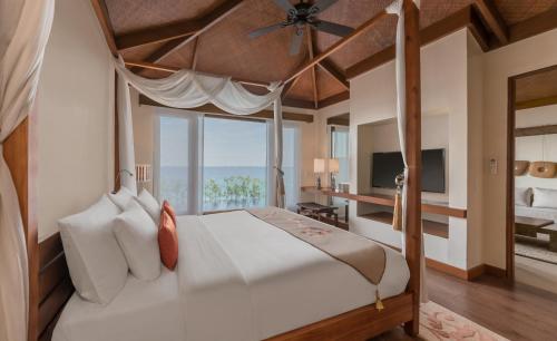 麦克坦Crimson Resort and Spa - Mactan Island, Cebu的一间卧室设有一张大床和大窗户