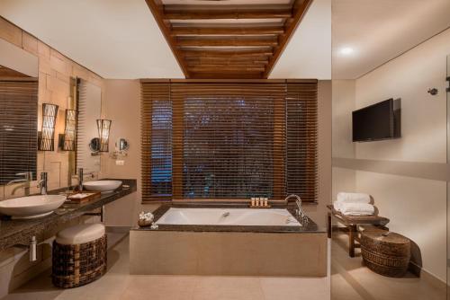 麦克坦Crimson Resort and Spa - Mactan Island, Cebu的一间带浴缸和两个盥洗盆的浴室以及一台电视。