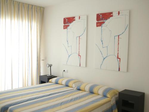 埃斯塔蒂特Apartamentos Rodamar的卧室配有一张床,墙上挂有两幅画