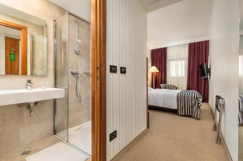 萨格勒布杜布罗弗尼克酒店的带淋浴和盥洗盆的浴室以及1张床。
