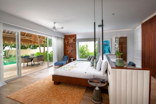 鲁阿环礁Emerald Maldives Resort & Spa-Deluxe All Inclusive的卧室配有一张床和一张桌子及椅子
