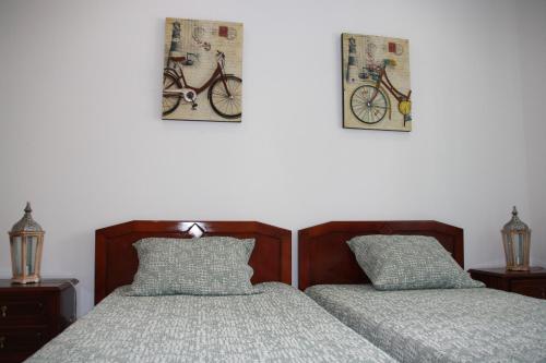 维拉·雷阿尔·德·桑托亚House of Orchids with Pátio的卧室配有两张床,墙上挂有两张自行车照片