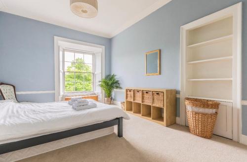 爱丁堡New Town Apartment with Castle View的一间拥有蓝色墙壁的卧室、一张床和窗户