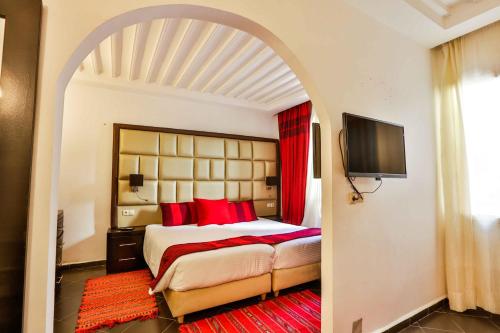 索维拉Hôtel Mechouar Plaza的一间卧室配有一张带红色枕头的大床