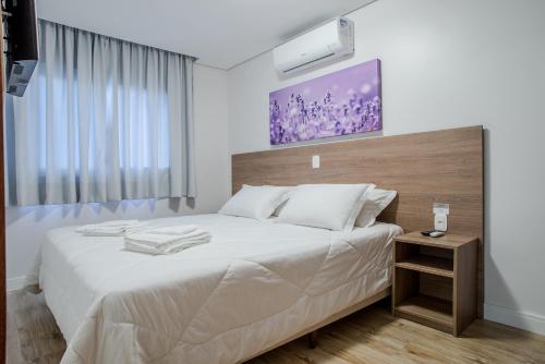 格拉玛多Monte Felice Stay - Parque da Vinícola的卧室配有一张白色大床和木制床头板