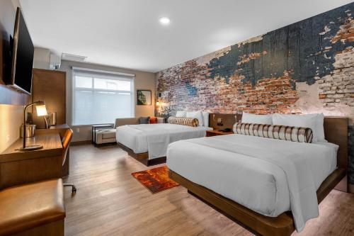 奥马哈Cambria Hotel Omaha Downtown的酒店客房带两张床和砖墙