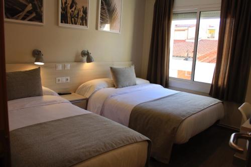 萨瓦德尔Hostal La Romànica的酒店客房设有两张床和窗户。