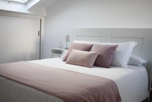 诺雅Apartamento Noia Centro Izqda的卧室配有带粉红色枕头的大型白色床