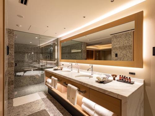 福冈福冈日航酒店的一间带大镜子和浴缸的浴室