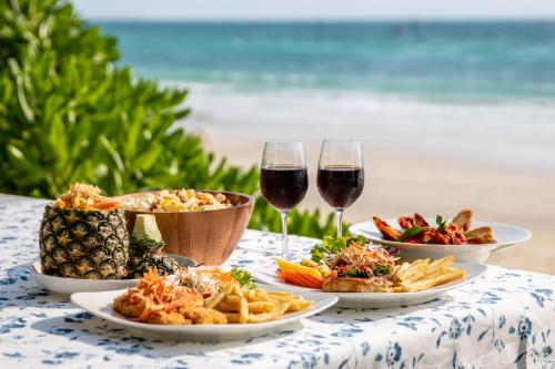 格兰岛世外桃源海滩度假村的一张桌子,上面放着三盘食物和两杯葡萄酒