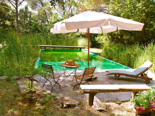 CerbaiaApartment Il Poggio by Interhome的一个带遮阳伞和桌椅的庭院,毗邻一个游泳池