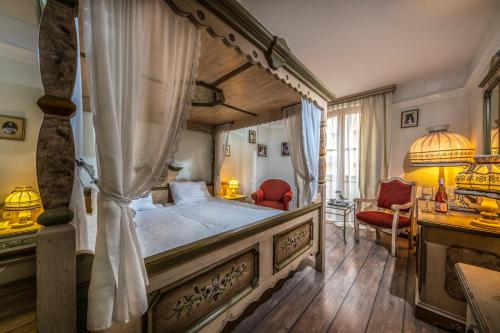 布达佩斯布达佩斯茜茜之翼柯文酒店的一间卧室配有一张天蓬床和一张书桌