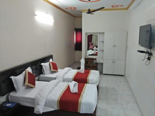 KushinagarHOTEL BUDDHA的酒店客房设有三张床和电视。