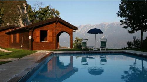 加尔尼亚诺Residence Hotel Montegargnano的一座带遮阳伞的房屋前的游泳池