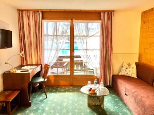 伊瑟尔特瓦尔德湖畔小屋酒店的带沙发、书桌和窗户的客厅