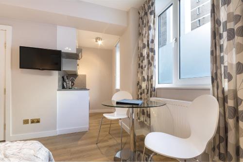 伦敦切尔西静谧酒店的一间小公寓,配有玻璃桌和白色椅子