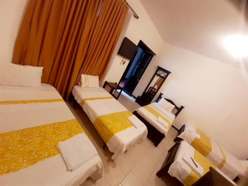 波帕扬Hotel y Restaurante Colonial Popayan的酒店客房设有两张床和窗户。