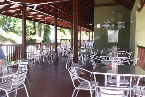 塔卡马卡冲浪者海滩自助式小屋酒店的一间空餐厅,配有桌子和白色椅子