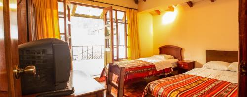奥塔瓦洛Casa del Huesped的客房设有两张床、一台电视和一扇窗户。