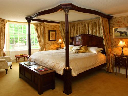 诺斯阿勒顿门廊之家住宿加早餐旅馆的一间卧室配有一张大天蓬床和一把椅子