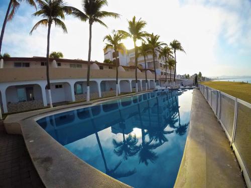 曼萨尼约马贝拉酒店的棕榈树建筑前的游泳池