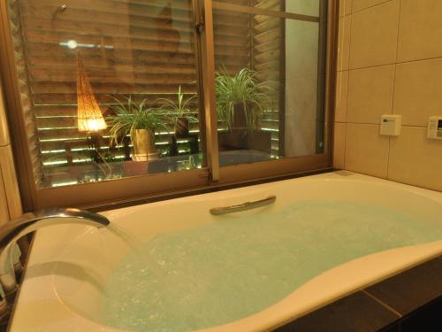 猪苗代町Cottage All Resort Service / Vacation STAY 8445的浴缸,带窗户和一些植物