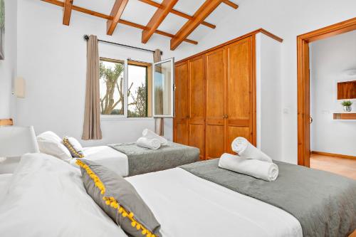 休达德亚Villa Flomertor 1 by Mauter Villas的卧室设有三张床,卧室拥有白色的墙壁和木制橱柜。