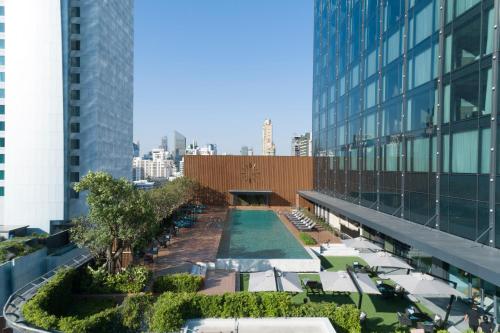 曼谷Carlton Hotel Bangkok Sukhumvit的享有带游泳池和椅子的大楼的顶部景致