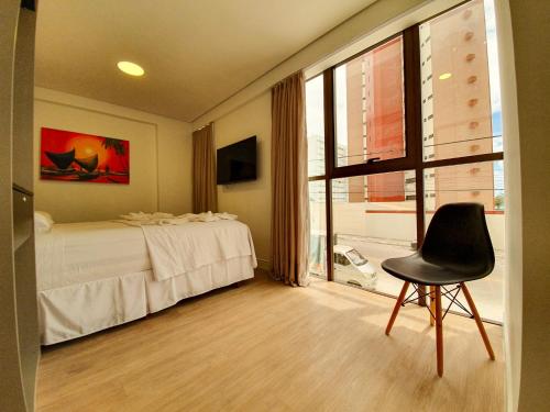纳塔尔Easy Suites Natal的卧室配有床、椅子和窗户。