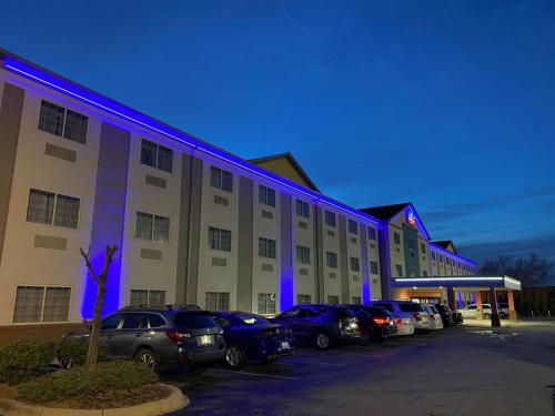 路易斯威尔SureStay Plus by Best Western Louisville Airport Expo的停车场内停放汽车的大型建筑