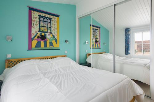 拉弗洛特Maison Amande的一间蓝色卧室,配有两张床和镜子