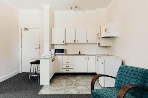 麦夸里港麦夸里港口酒店的厨房配有白色橱柜和蓝色椅子