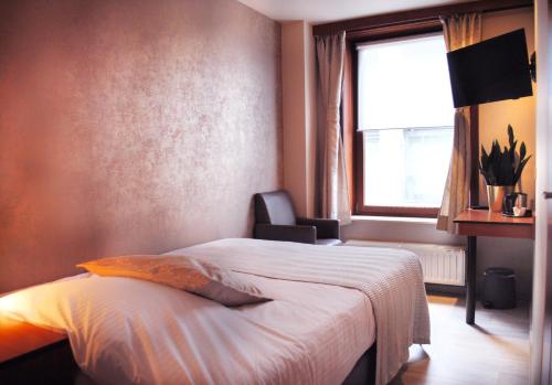 奥斯坦德Hotel Rubens的一间卧室设有一张床、一个窗口和一把椅子
