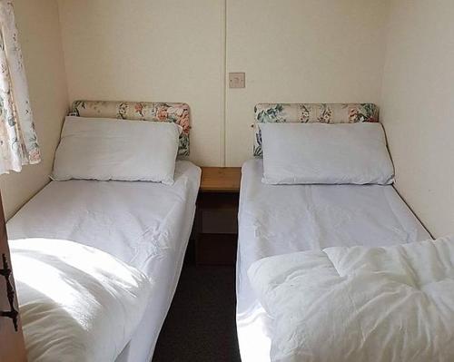 查珀尔圣伦纳兹Caravan Golden Palm的小客房内的两张床,配有白色床单