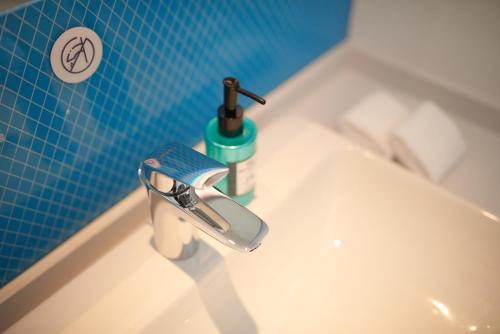杭州杭州九州智选假日酒店的浴室水槽设有水龙头和蓝色瓷砖