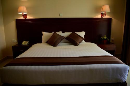 基加利诺布莱扎酒店的一间卧室配有一张大床和两盏灯