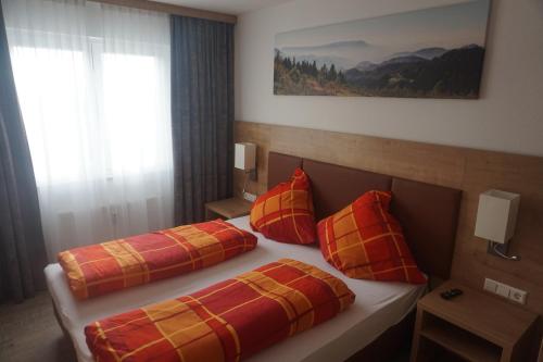 费尔德伯格Ferienwohnung Gipfelstürmer Feldberg - Ski in Ski out, Whirlpool & Infrarotkabine的一间卧室配有两张带红色和橙色枕头的床