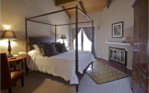 蒙特雷Merritt House Hotel的一间卧室设有一张天蓬床和一个壁炉