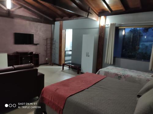 卡皮托利乌Chalés da Zelma的一间卧室配有两张床、一张沙发和一台电视