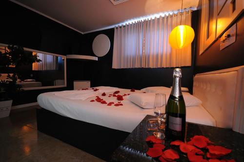 卡拉济纽Motel Paradiso Carazinho (Adults Only)的一间卧室配有一张床,提供一瓶葡萄酒和鲜花